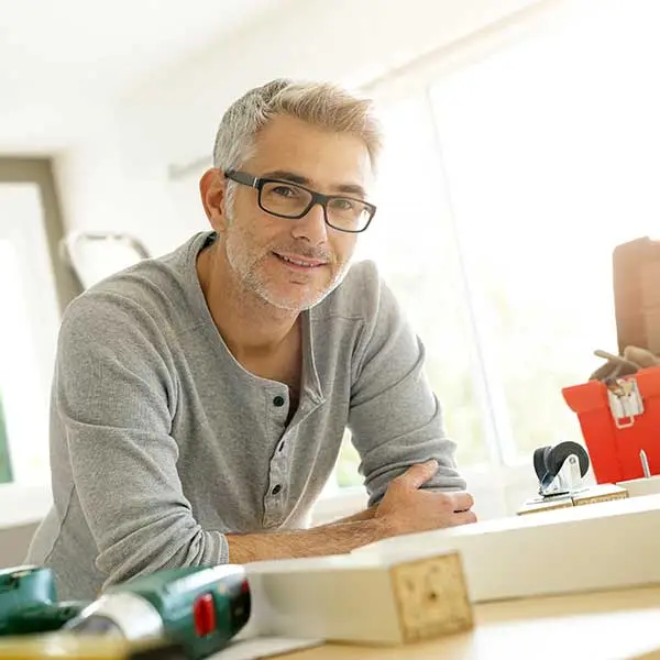 Smiling older man leaning over a wooden table