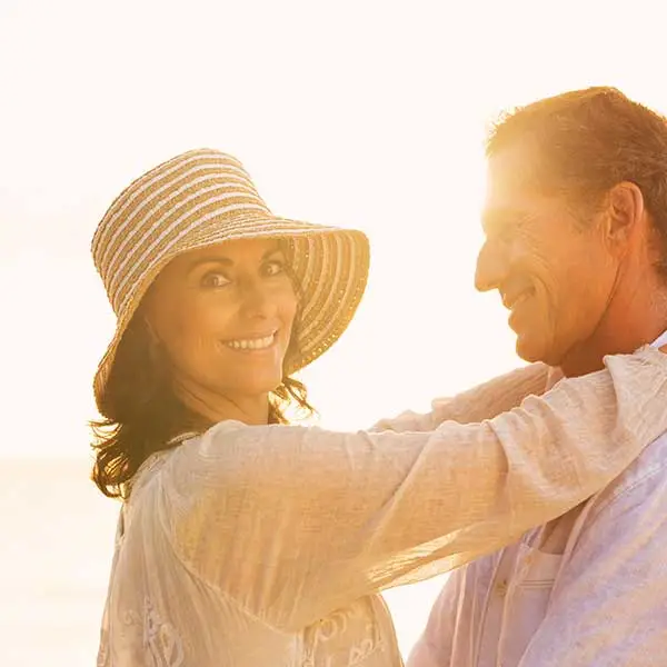 Older couple holding each other in front of a sunset