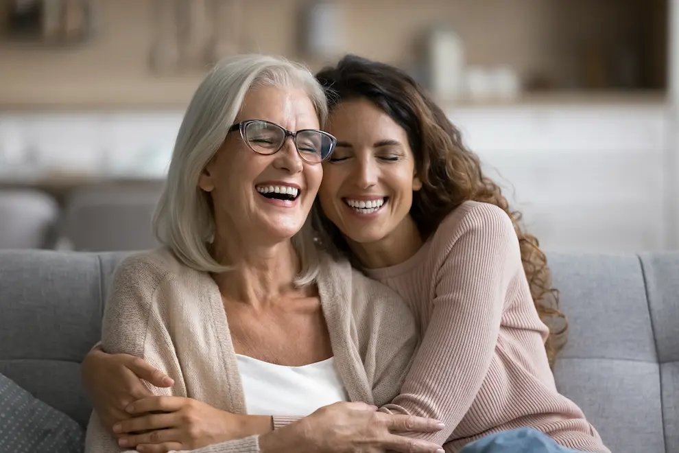 Older and younger women hugging each other and laughing